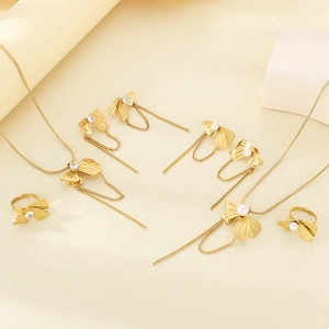 Detailed view of polished gold bow jewelry set with tassel chains and white pearls