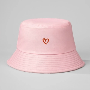 Close-up of pink cotton bucket hat featuring red embroidered heart detail and fine fabric texture