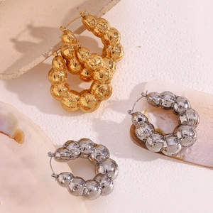 Close-up of golden and silver hollow hoop earrings with unique bubble texture finish