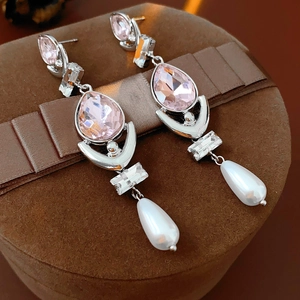 Macro detail of drop earrings with pink stones and pearls on a velvet jewelry box