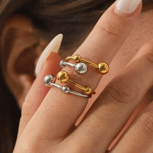 Close-up of minimalist two-tone stacked rings with metal beads on finger