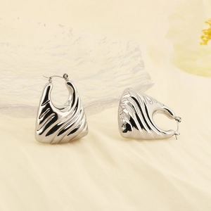 Close-up of silver-tone U-shaped earrings with textured vertical striped pattern