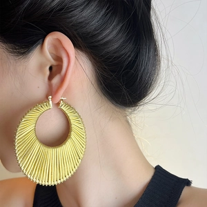 Boucles d'oreilles créoles dorées vintage avec texture radiale sur un mannequin