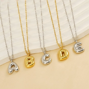 3D bubble alphabet necklaces in gold and silver finish with fine cable chains on a tray