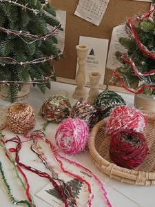 Colorful Christmas DIY yarn balls in a festive setting with mini trees and wicker tray