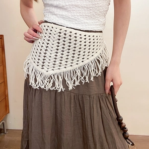 Detailed macro view of white crochet knit lace pattern and long fringe on the triangle scarf