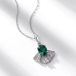 Elegant silver fan-shaped necklace with emerald green stone and sparkling diamond accents