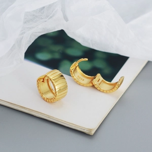 Macro view of 925 silver golden hoop earrings with vertical wide stripe texture