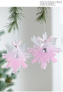 Pink glitter snowflake ornaments with crystal center and silk bow on green pine branch