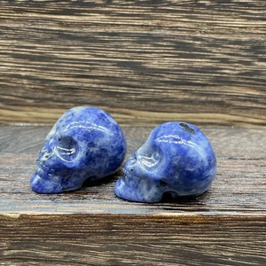 Close-up of small blue natural stone crystal skulls with polished marble texture