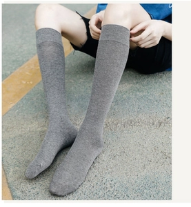 Detailed close-up of grey knee-high knit socks with fine texture on a model's legs