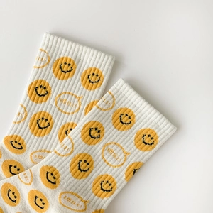 Close-up of knit cotton mid-tube socks featuring yellow smiley face and smile text