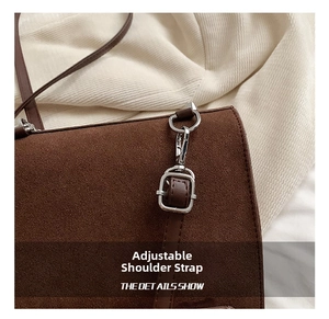Detalle de la correa ajustable con hebilla de metal plateado en bolso de ante marrón