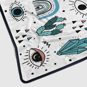 Close-up of bohemian flannel blanket with evil eye and cactus prints on soft fabric