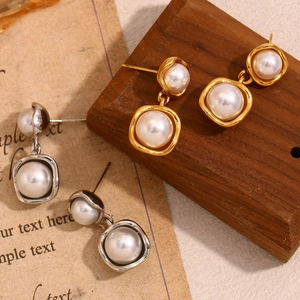 Elegant 18K gold and silver plated stainless steel pearl stud earrings on vintage wood