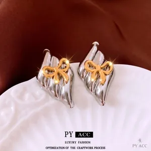 Two-tone silver leaf earrings with gold bow detail in a stylish minimalist design