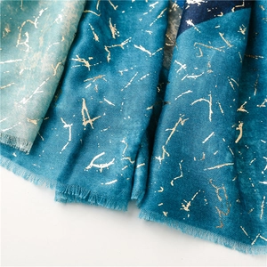 Detailed close-up of blue gradient scarf featuring gold foil prints and fine fringe trim