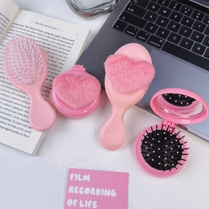Pink plush heart hairbrush set with portable folding mirror comb on a desk