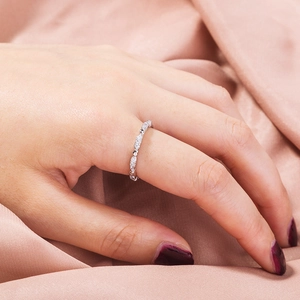 Close-up of a silver ring with micro-paved zircons worn on a finger over pink silk
