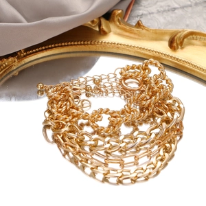 Multi-layer gold metal thick chain bracelet set displayed on a gold framed mirror