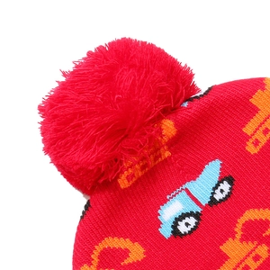 Close-up of a red knit beanie for kids showing the fluffy pom-pom and high-quality yarn