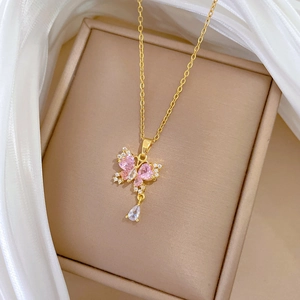 Dettaglio macro della collana con ciondolo a farfalla dorata con strass rosa nel cofanetto