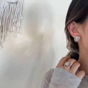 Close-up of floral silver zircon earrings and ring set worn on a model with yellow centers