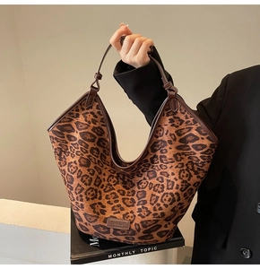 Detailed view of leopard print tote bag featuring brown leather straps and texture