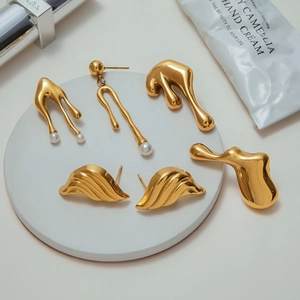 Detailed close-up of golden lava earrings with pearls on a white stone pedestal