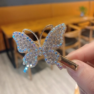 Elegant gold butterfly hair clip with colorful rhinestones held by a hand