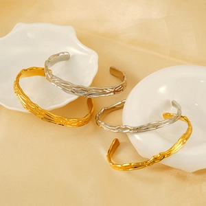Close-up of gold and silver twisted bangles with hammer texture on silk background