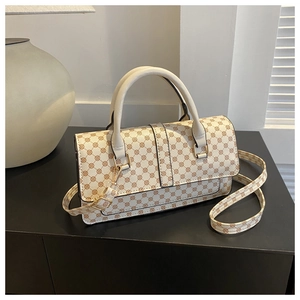 Close-up of cream white monogram handbag with brown leather handles and shoulder strap