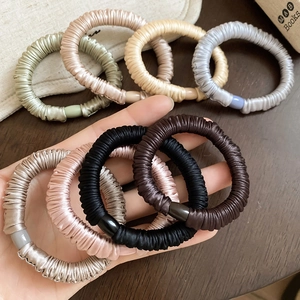 Close-up of assorted silk-textured elastic hair ties in neutral and earth tones