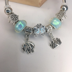 Silver charm bracelet with elephant, crown, pumpkin carriage pendants and blue glass beads