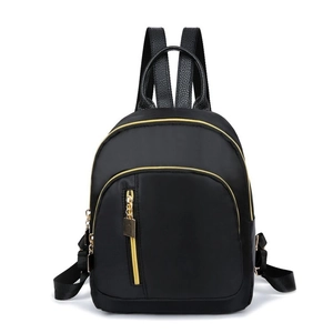 Detail of black nylon backpack featuring premium leather handles and gold metal zippers