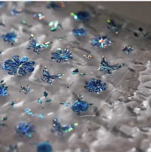 Macro shot of iridescent laser nail stickers with blue butterflies and floral motifs