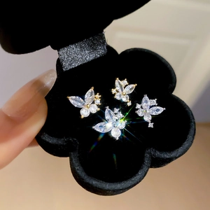 Close-up of sparkling butterfly and flower zircon stud earrings in a black jewelry box