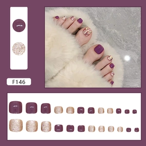 Deep purple and champagne gold glitter press-on toe nails on white fur background
