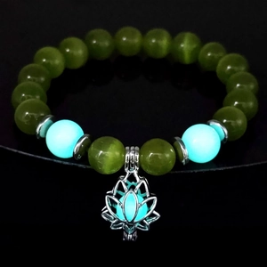 Detailed macro view of luminous lotus bracelet with glowing blue beads and dark green stones