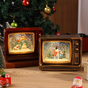 Cozy scene with lit vintage TV snow globes on a wooden surface by a Christmas tree