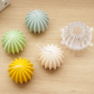 Detail of transparent spherical candle mold and finished ribbed cactus style candles