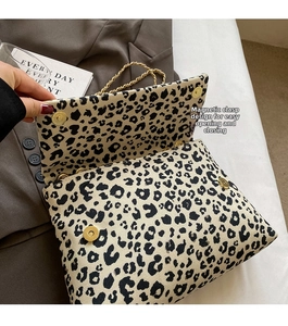 Detail of leopard print tote bag featuring a gold magnetic snap and chain strap