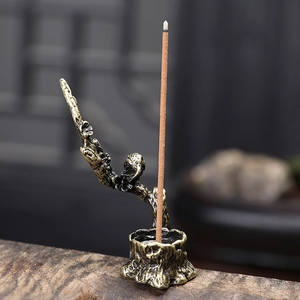 Dettaglio del porta incenso in bronzo vintage con fiori di prugno e uccellino inciso