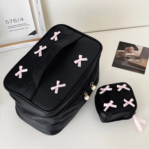 Detail of black nylon makeup bags featuring pink bows and elegant pearl zipper pulls