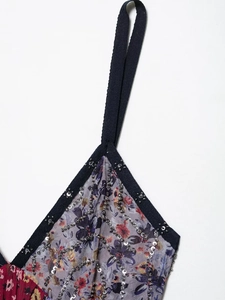 Dettaglio di abito a fiori con bordo in perline nere e paillettes sull'attacco spalline