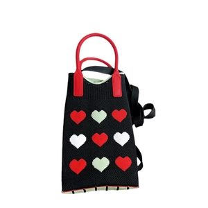 Detail of black knit phone bag with red heart pattern and adjustable shoulder strap