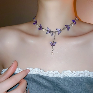Detail of butterfly choker necklace with purple crystal wings and pearls on skin