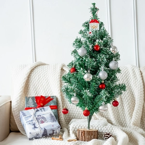 Miniature Christmas tree gift set with red ornaments and wooden base on cozy white blanket
