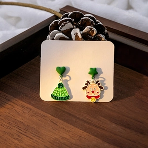 Détail de boucles d'oreilles de Noël avec renne et bonnet sur plateau bois