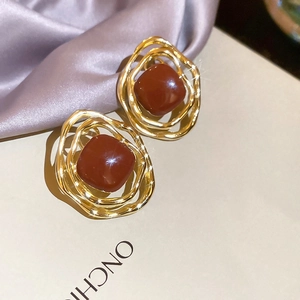Gros plan de boucles d'oreilles spirales dorées vintage avec une pierre en résine marron